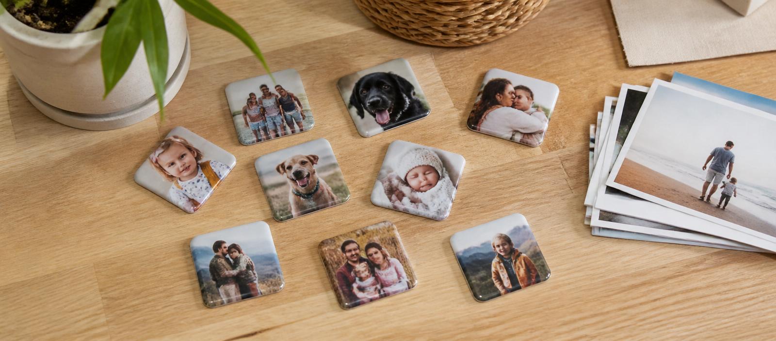 Custom photo magnets arranged on a wooden table beside a stack of printed photos